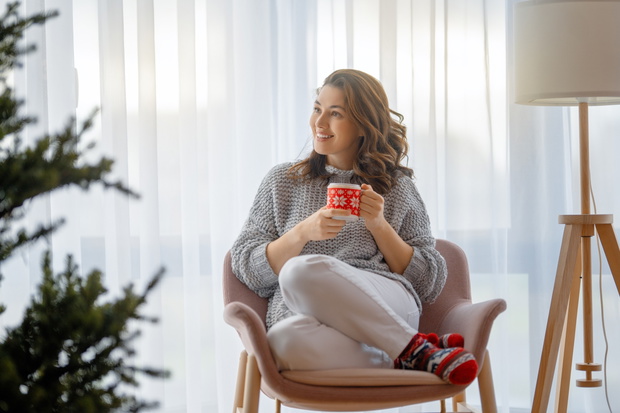 woman drinking coffee near Christmas tree