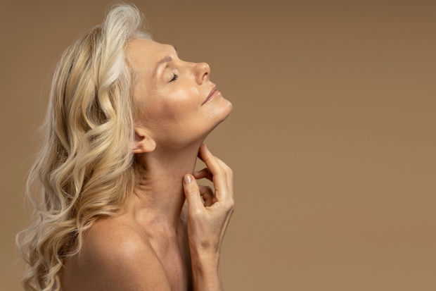 Beautiful blonde Caucasian 50-55 years mature woman posing with closed eyes isolated