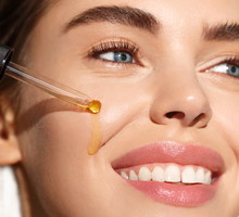Skin care. Young woman apply moisturizing facial serum, hand holding dropper with essential oil, isolated on white background. Skincare and rejuvenation concept