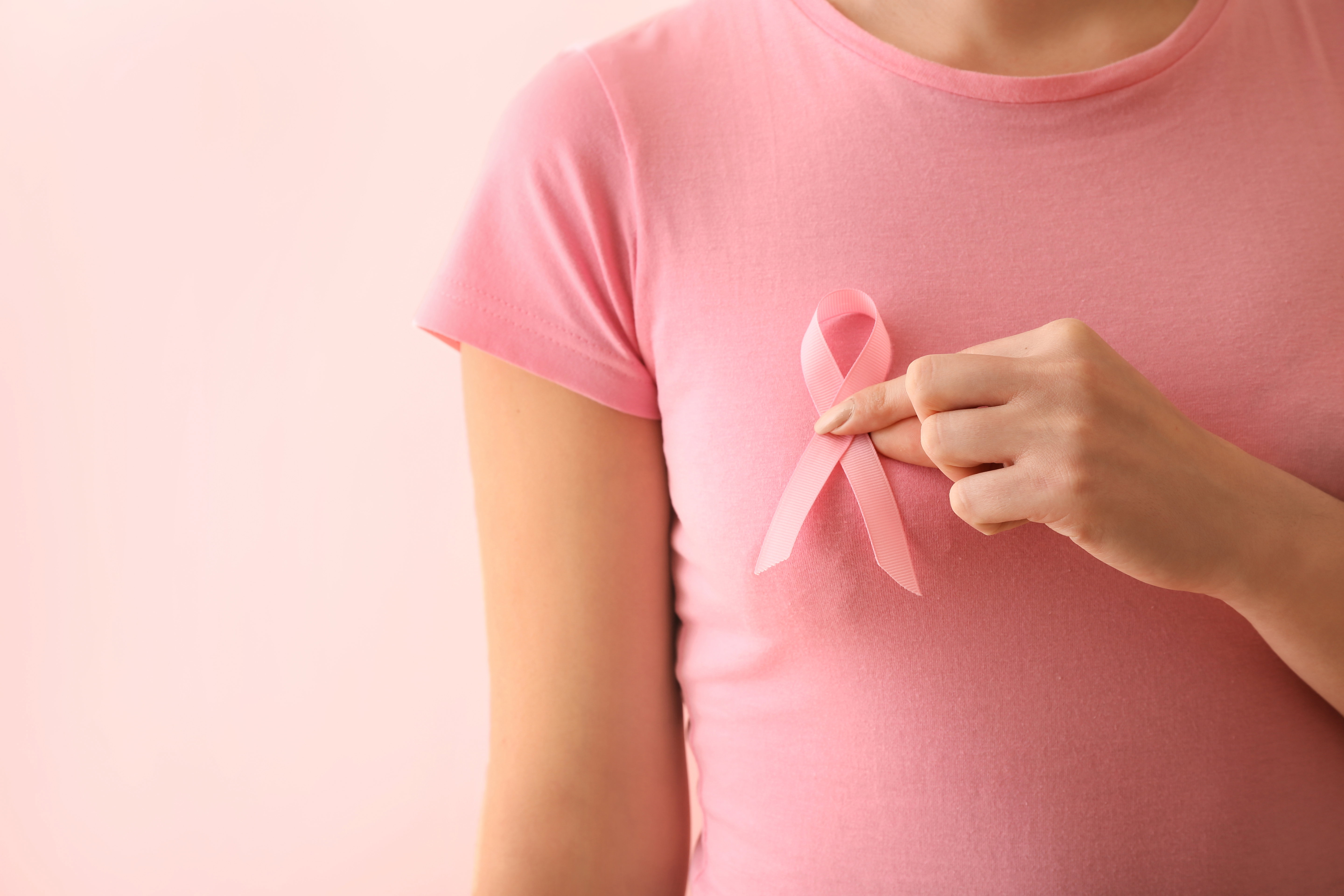 Woman with pink ribbon on color background. Breast cancer awaren