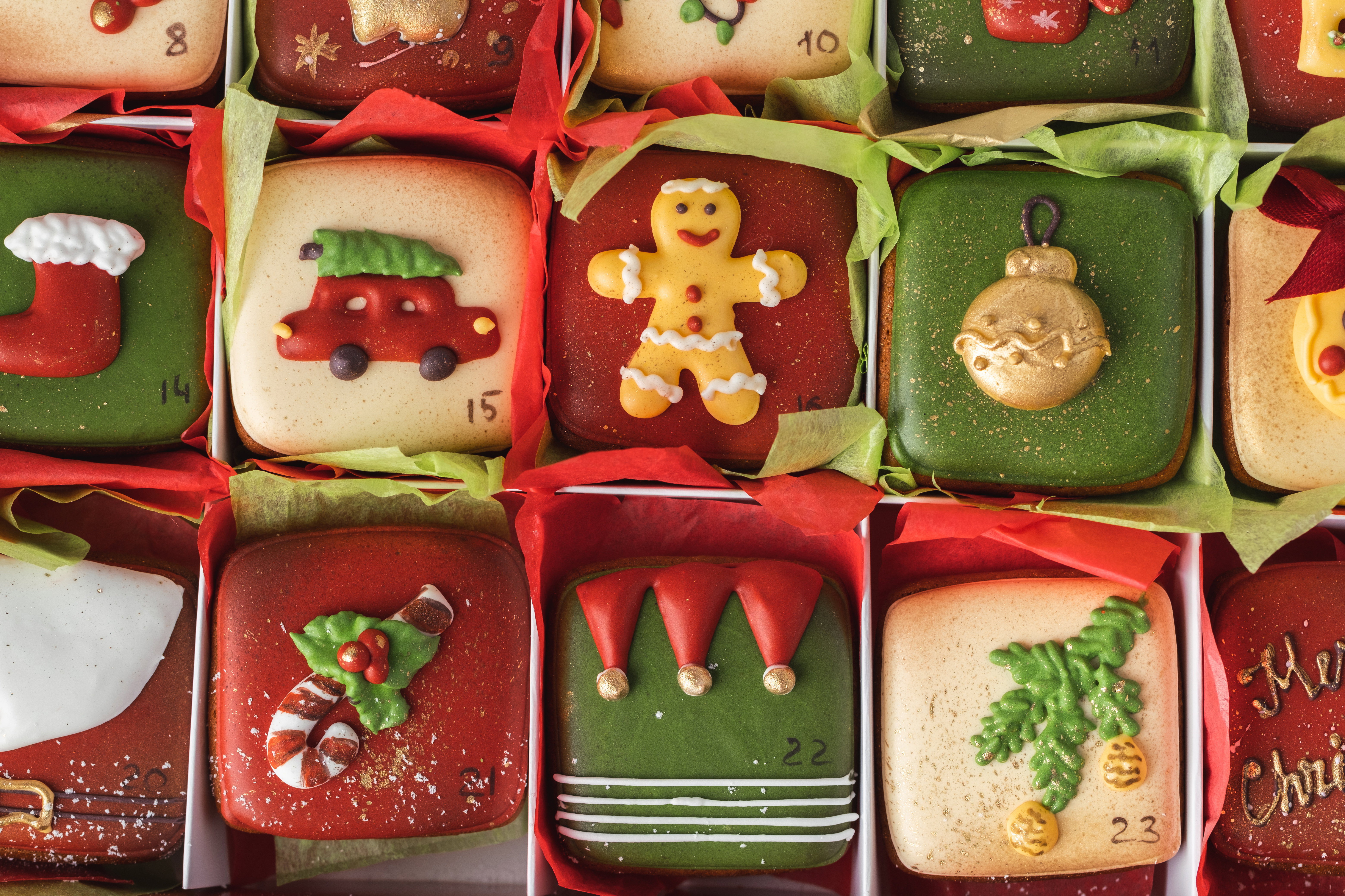 Delicious Christmas cookies set in a gift box. Advent calendar to count the days in anticipation of Christmas. Gingerbread cookies with festive red and green icing on the Christmas background