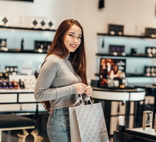 Happy beautiful Asian girl smiling young girl buys perfume cosmetics in the store