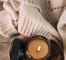 Candle in small amber glass jar with wooden wick on wooden stand on background. Top view