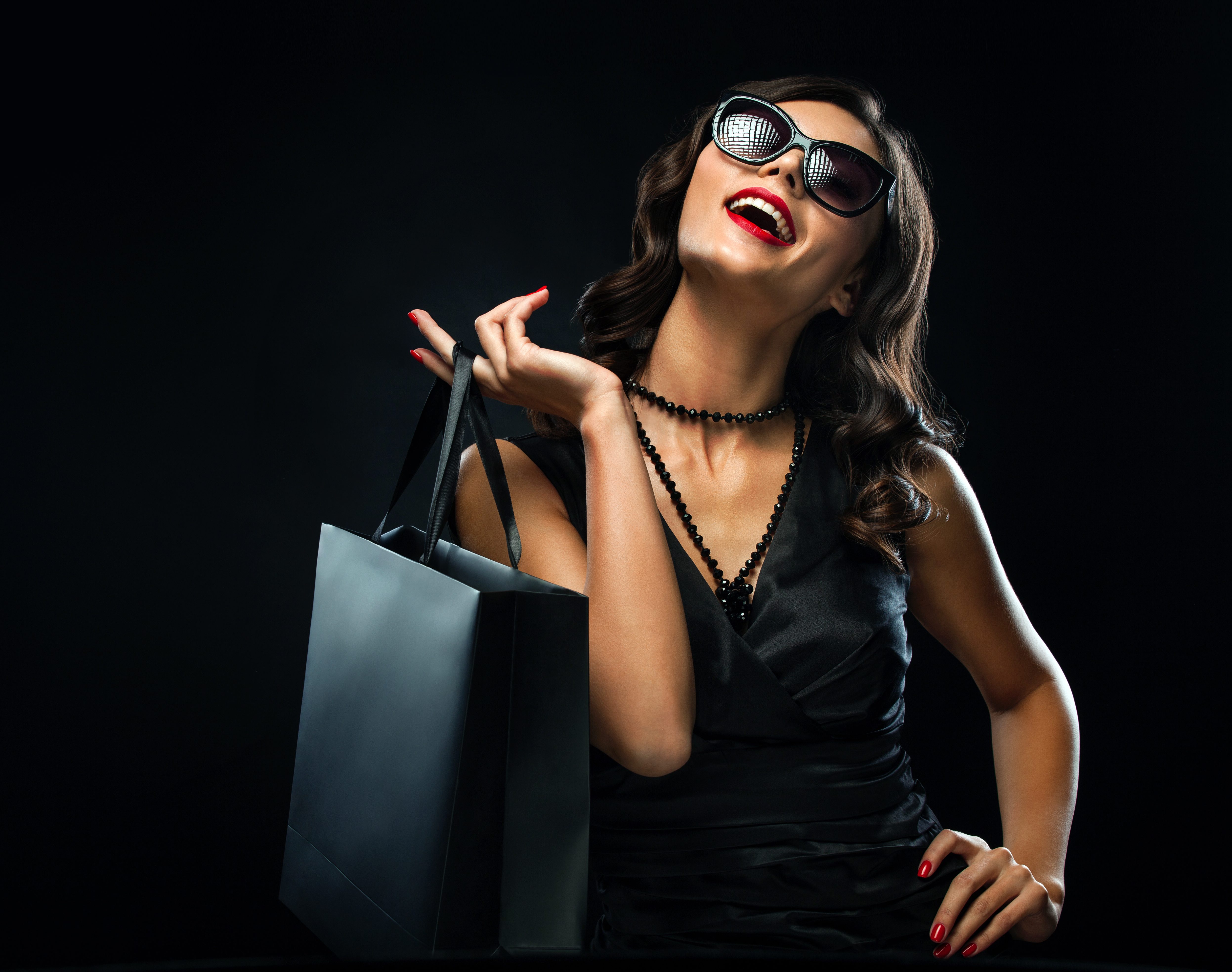 Black friday sale concept. Shopping woman holding grey bag isolated on dark background in holiday