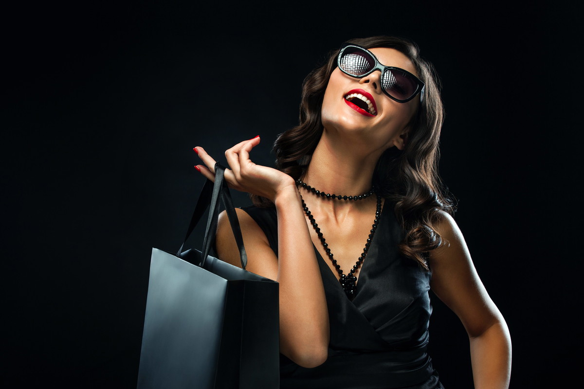Black friday sale concept. Shopping woman holding grey bag isolated on dark background in holiday