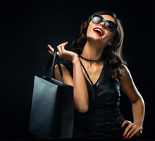 Black friday sale concept. Shopping woman holding grey bag isolated on dark background in holiday