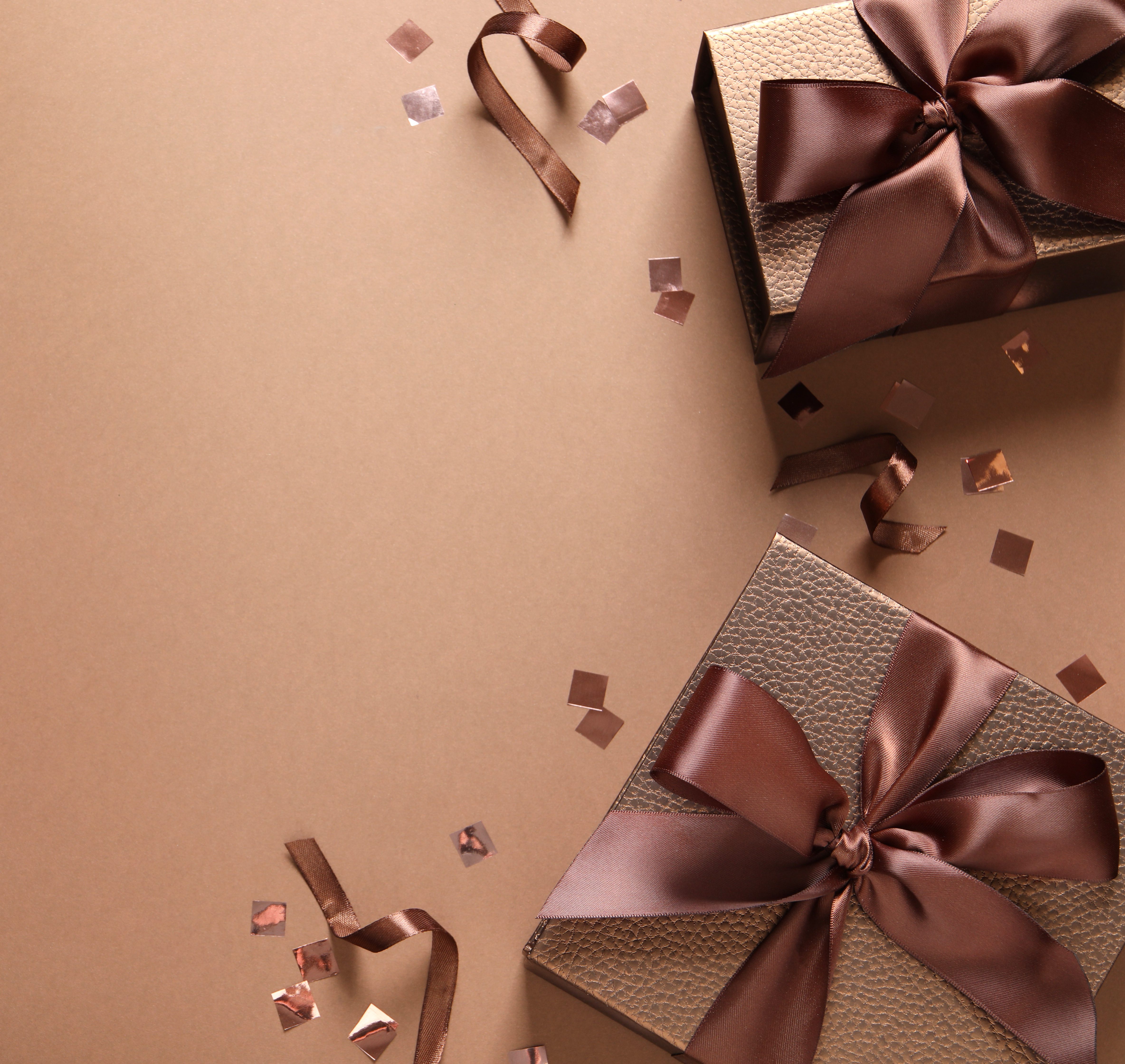 Beautiful gift boxes and confetti on brown background, flat lay. Space for text
