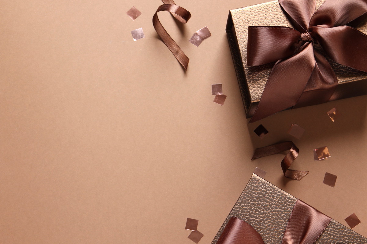 Beautiful gift boxes and confetti on brown background, flat lay. Space for text