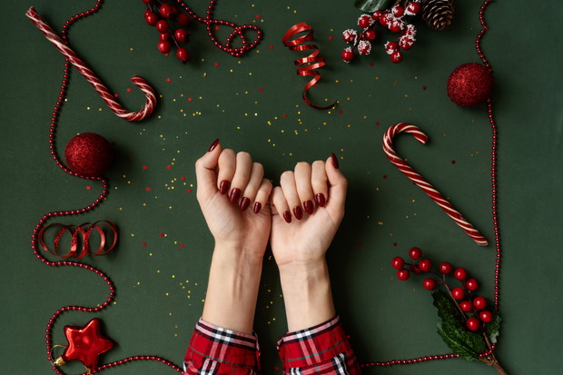 Christmas manicure. Red nails on green background.