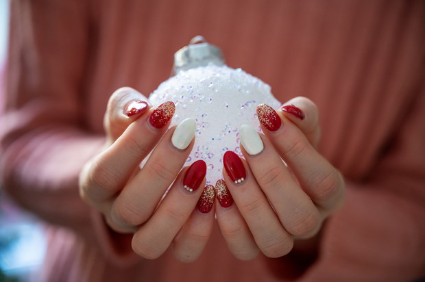 Female hands with stylish holiday manicure holding shiny white c