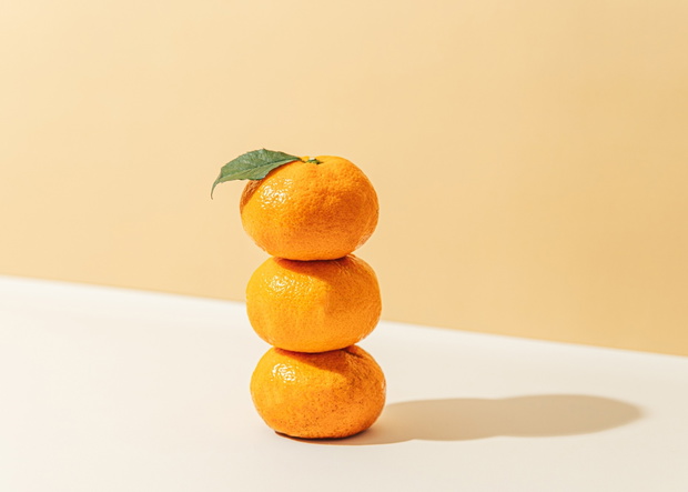 Mandarin oranges stacked against orange background