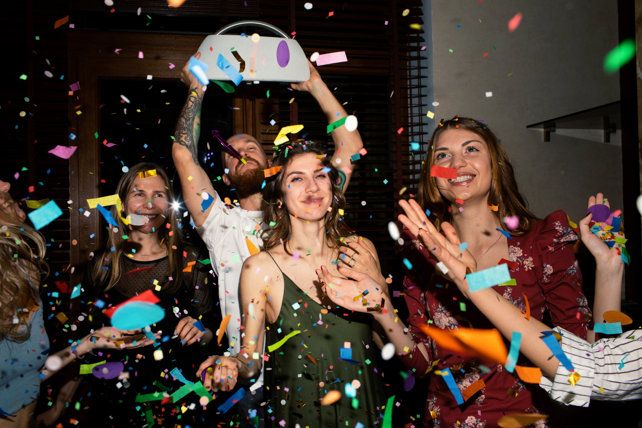 Group of friends having fun with confetti at home.