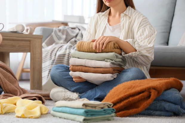 Young,Woman,With,Stacks,Of,Clean,Clothes,Sitting,On,Floor