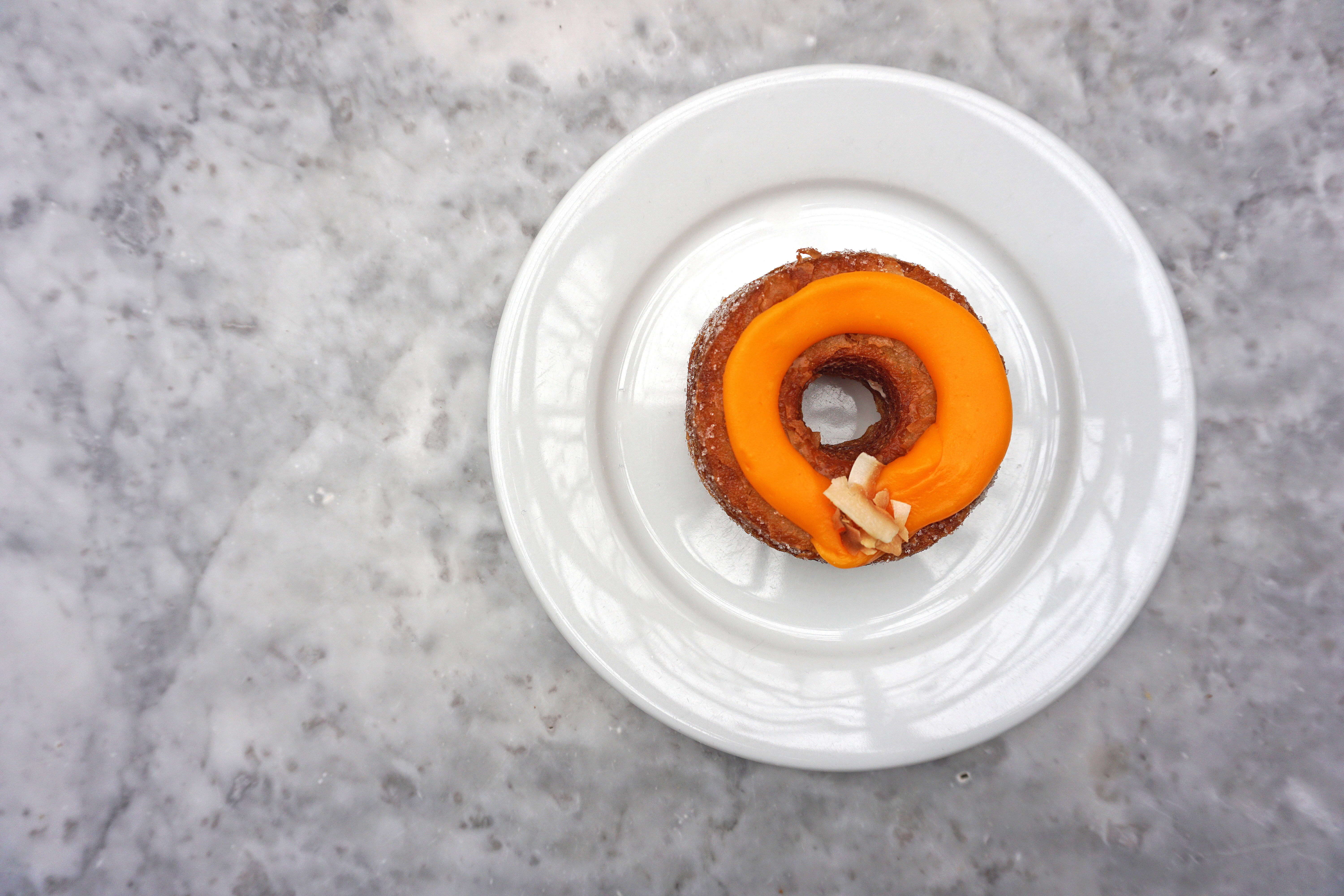 Close up Cronut (combination of croissant and doughnut) Topped with Passion fruit jam and toasted coconut Ganache