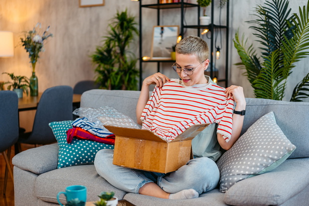 Mid-Adult Woman Unboxing A Package With New Shirt She Ordered Online
