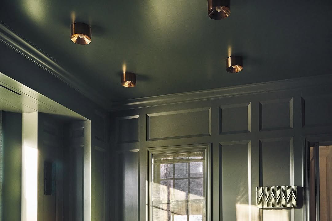 ON THE HOUSE For this private residence lounge, the dark green high-gloss paint by Farrow & Ball sets a moody backdrop. A vintage Ilum Wikkelso loveseat adds character, facing a bespoke stone coffee table by Sung Jang. Erin Trefry’s artwo