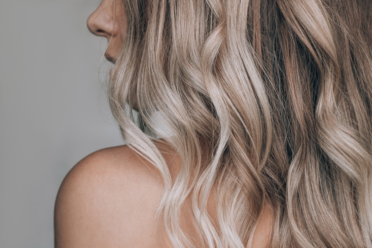 Close-up of the wavy blonde hair of a young blonde woman isolate