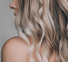 Close-up of the wavy blonde hair of a young blonde woman isolate