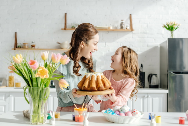 excited mother and child looking at each other near easter eggs,