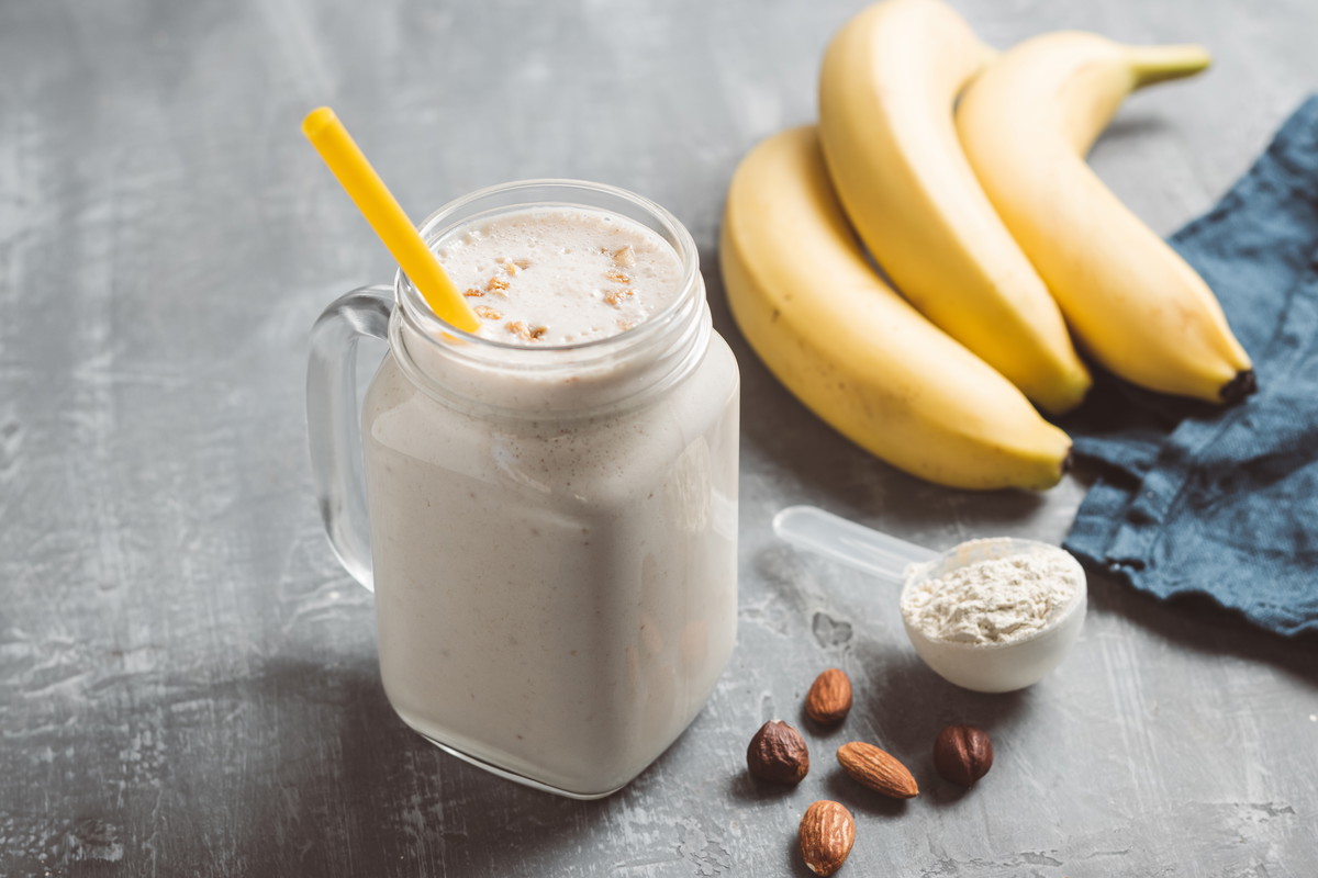 Banana smoothie with protein powder and nuts in a glass jar, healthy eating concept