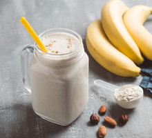 Banana smoothie with protein powder and nuts in a glass jar, healthy eating concept