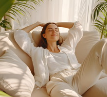 Happy woman relaxing on comfortable soft sofa enjoying stress free weekend at home, calm satisfied girl stretching on couch thinking of pleasant lazy day, dreaming and planning sunday morning.