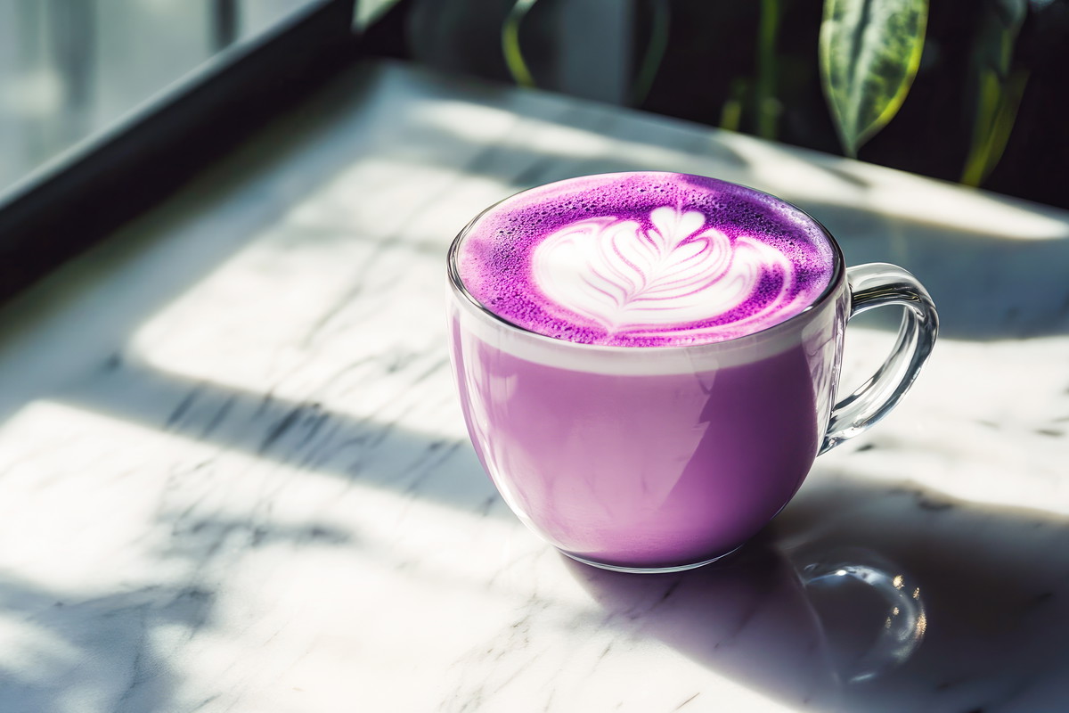 Trendy Purple Sweet Potato Latte With Milk Foam latte art. Purple sweet potato coffee in a cup on marble table with shadows. Trendy purple coffee recipe, cafe menu. Copy space