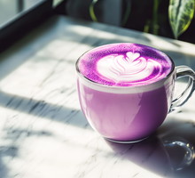 Trendy Purple Sweet Potato Latte With Milk Foam latte art. Purple sweet potato coffee in a cup on marble table with shadows. Trendy purple coffee recipe, cafe menu. Copy space