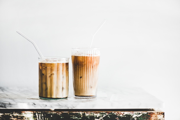Iced latte coffee in glasses with straws, whate wall background
