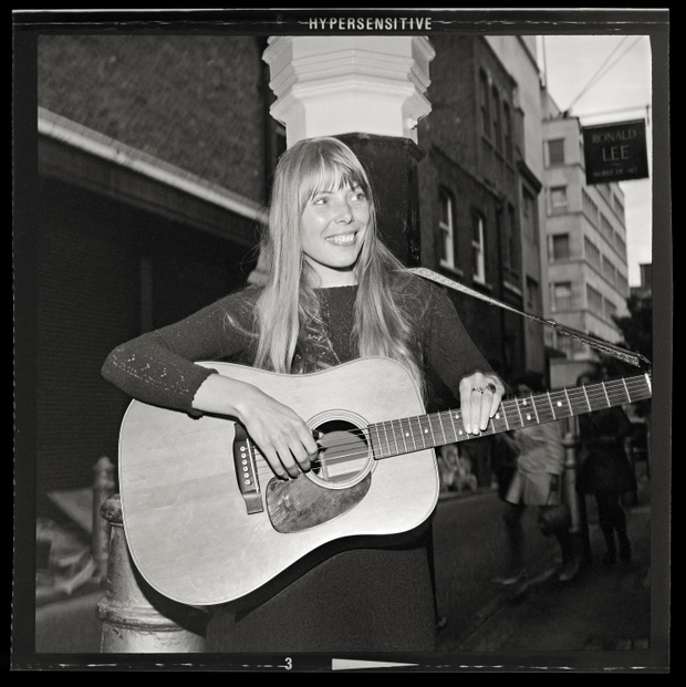 Joni Mitchell strums guitar outside the The Revolution Club, London, England, September 17, 1968. On tour for the release of her debut album Song to a Seagull.  Image from 2.25 X 2.25 inch negative.