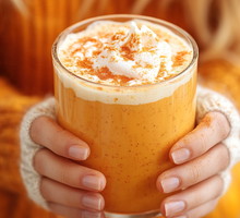 Woman holding glass of tasty pumpkin spice latte