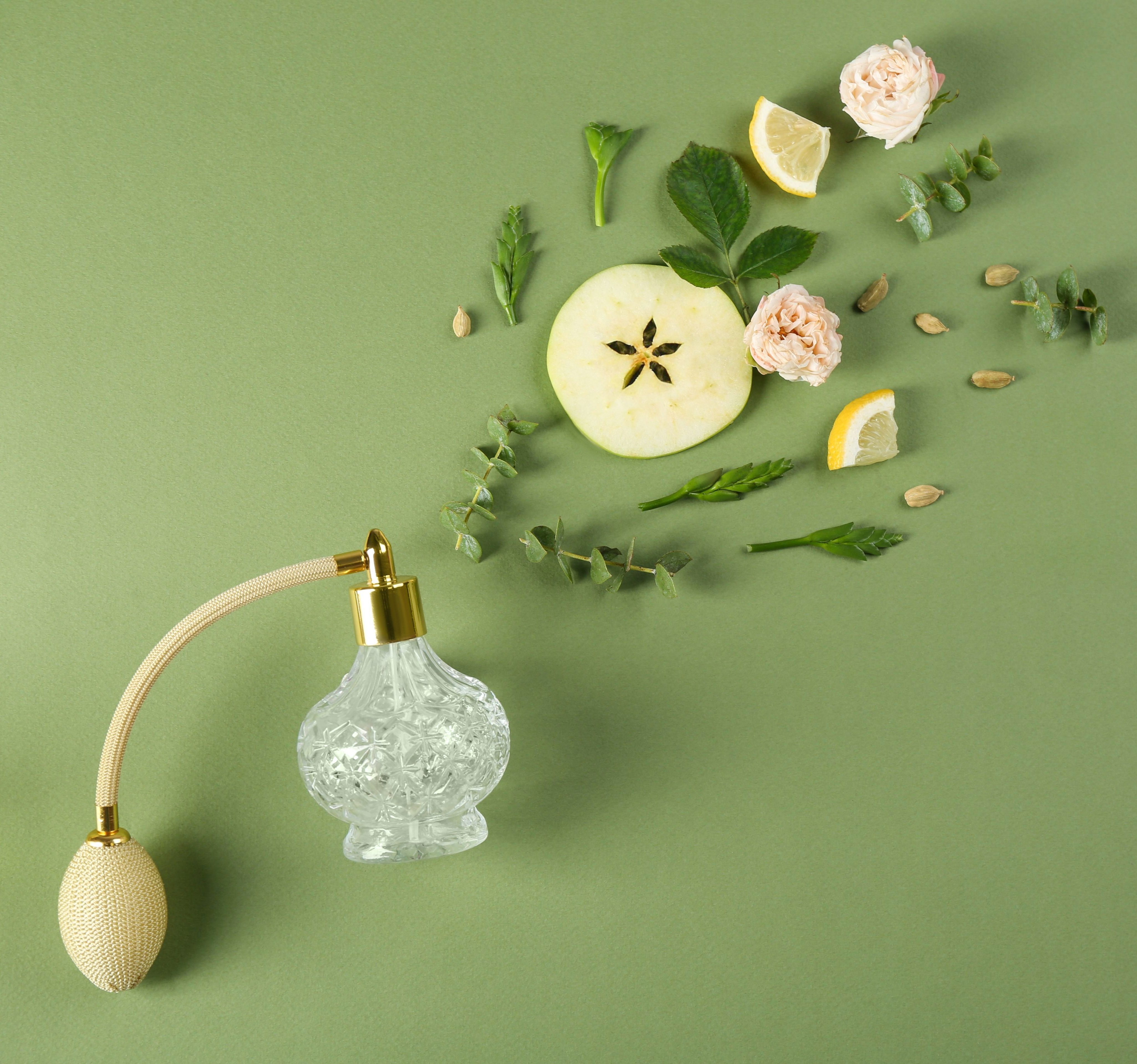 Flat lay composition with bottle of perfume on green background, space for text
