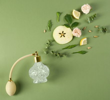 Flat lay composition with bottle of perfume on green background, space for text