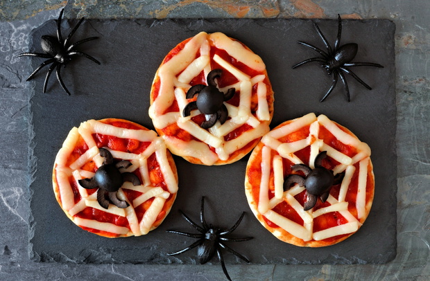 Halloween spider web mini pizzas, overhead view on a slate serve
