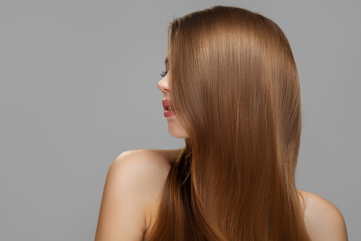Woman's clean styled hair. Half of the face is covered with brun