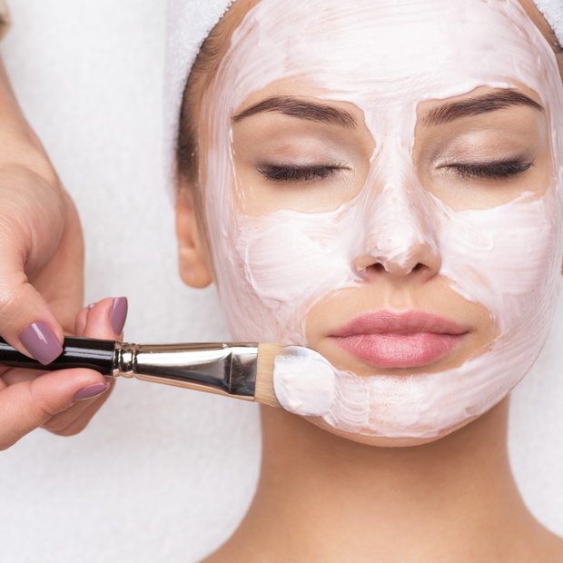 Woman receiving facial mask at beauty salon