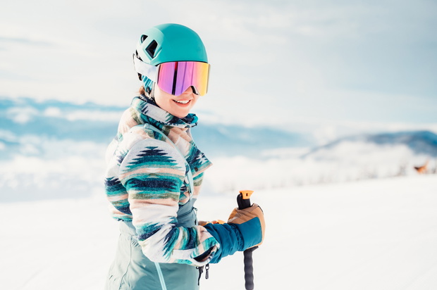 Woman in skiing clothes with helmet and ski googles on her head