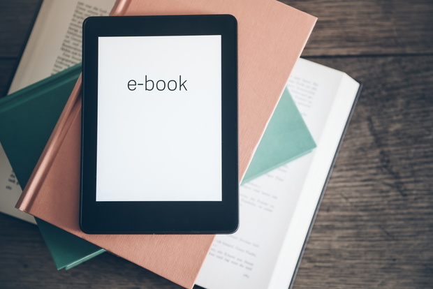 e-book reader on a stack of books on rustic wooden table concept
