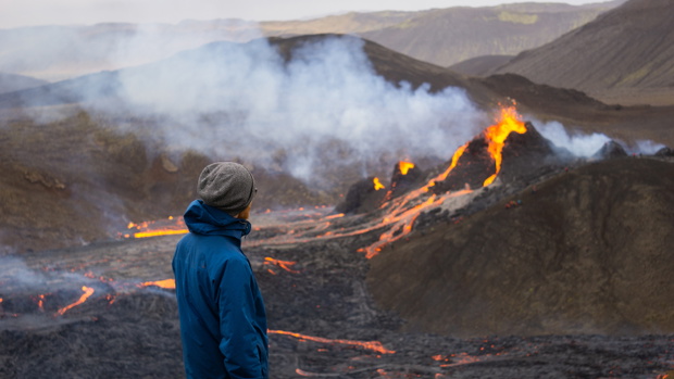 A hiker watches a small volcanic eruption in Mt Fagradalsfjall,