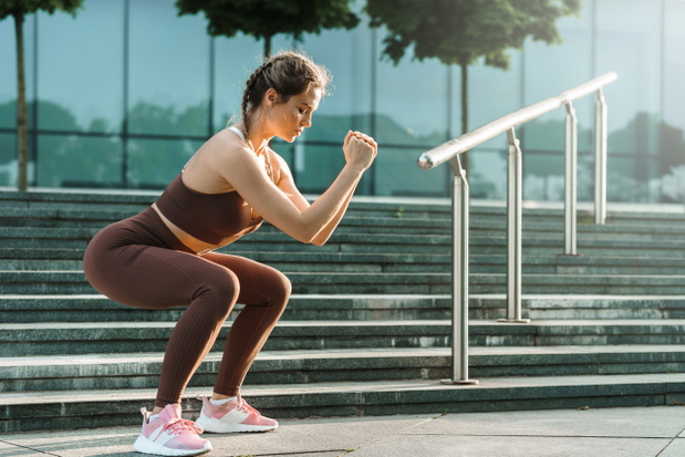 Athletic woman doing squats during her street workout