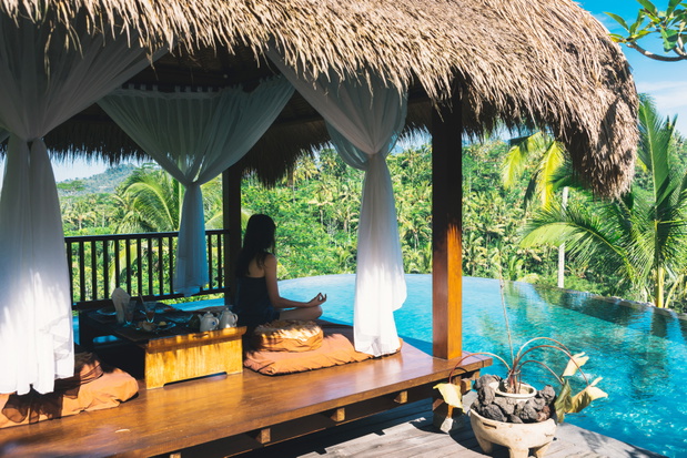 Girl meditating by the pool on a background of palms, Bali, Indonesia