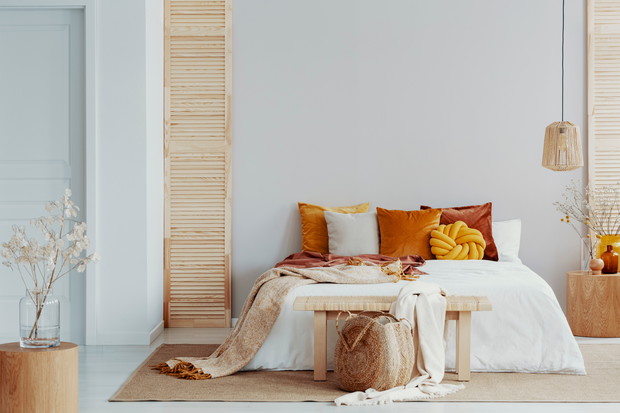 Brown and orange pillows on white bed in natural bedroom interio