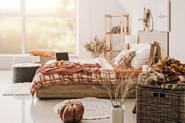 Stylish interior of room with big comfortable bed and autumn dec