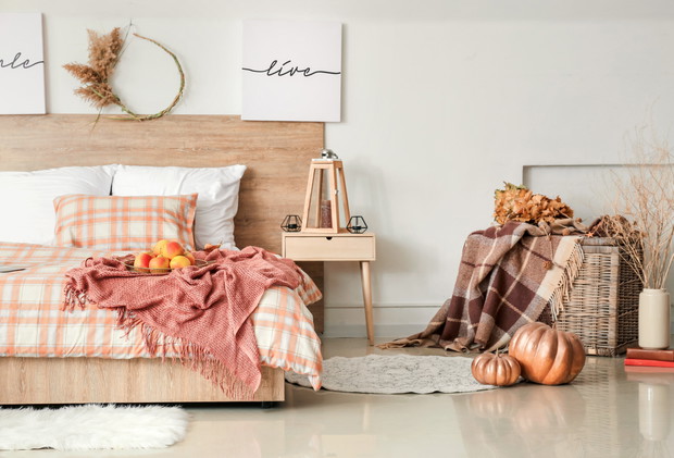 Stylish interior of room with big comfortable bed and autumn dec