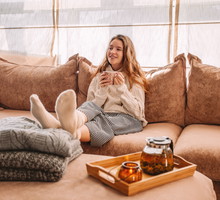 Happy woman relaxing on sofa at home on bright winter morning