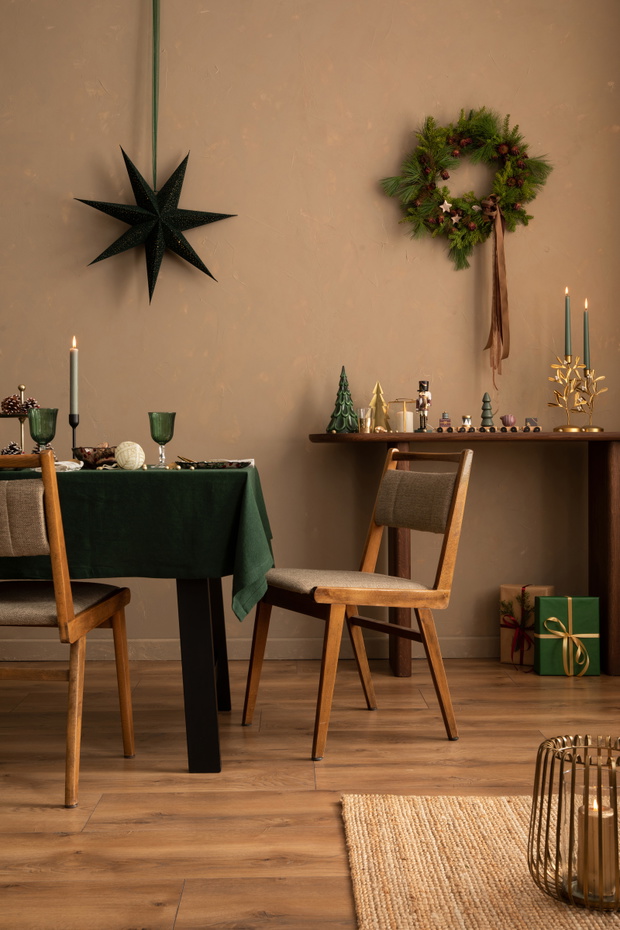 Interior design of warm dinning room interior with christmas table, wooden console, christmas gifts, gingerbread, candle, star on wall christmas wreath and personal accessories. Home decor. Template.