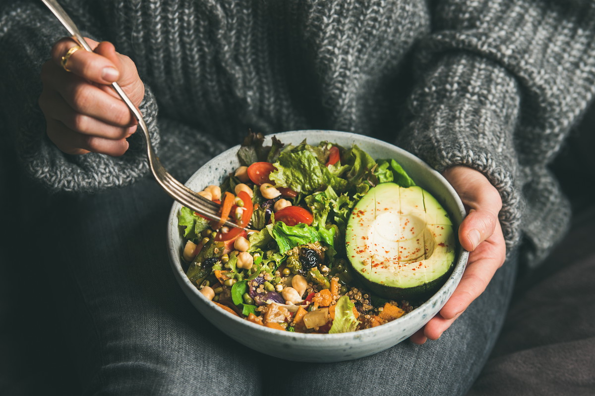 Woman eating healthy vegetarian dinner from Buddha bowl, close-up