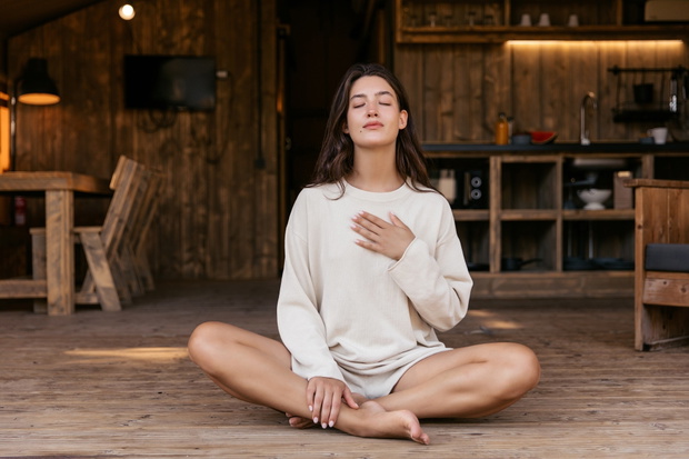 Cute young caucasian woman is doing yoga and stretching on terrace of her house outside city.