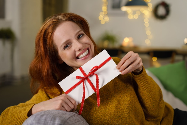 attraktive frau freut sich über einen gutschein zu weihnachten