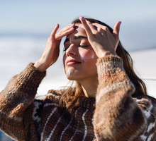 Young woman applying sunscreen on her face in snow landscape